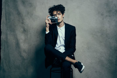 Young man photographing against wall