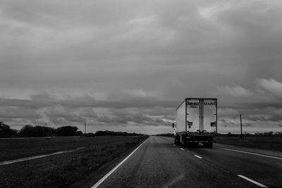 Semi-truck on highway against overcast clouds