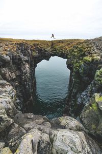 Scenic view of man jumping on cliff