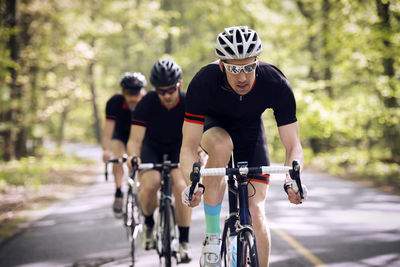 Confident male cyclist riding bicycle with friends on country road