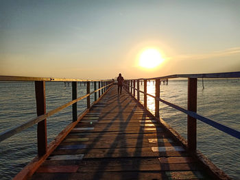 Pier over sea against sky during sunset