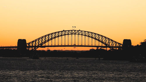 Silhouette bridge over river against sky during sunset