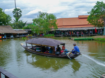 People in boat on canal against buildings