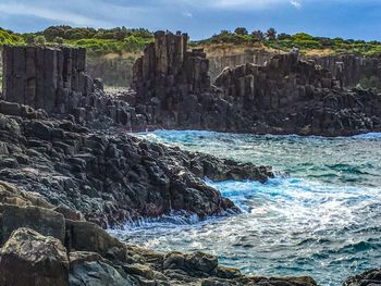 Scenic view of cliff by sea against sky