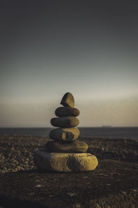 Stack of pebbles on beach against sky during sunset