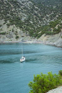 Sailboat sailing on sea against mountains