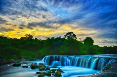 Scenic view of waterfall against sky during sunset