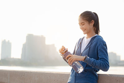 Young woman standing against clear sky in city