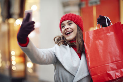 Portrait of smiling young woman using smart phone outdoors