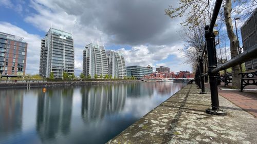 Buildings by river against sky in city