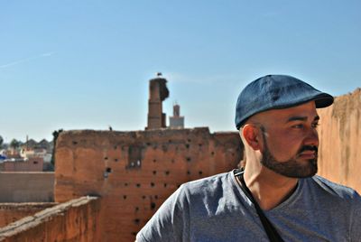 Portrait of young man against building against clear sky