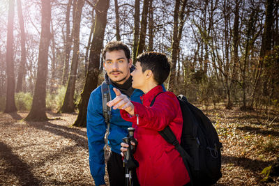 Beautiful young couple is hiking in the woods. the woman is pointing to her boyfriend.
