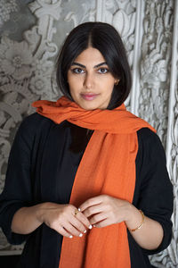 Portrait of young woman standing against wall