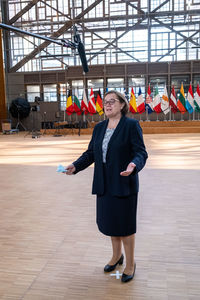 Full length portrait of a smiling young woman standing on floor