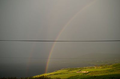 Scenic view of field against rainbow in sky