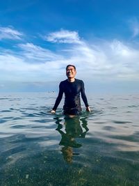 Smiling man standing in sea against sky