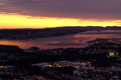 High angle view of townscape by sea against sky during sunset