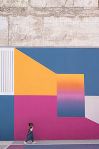 Side view of woman standing against multi colored wall