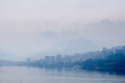 Sea by buildings against sky in city