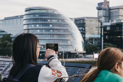 Rear view of man and woman using mobile phone in city