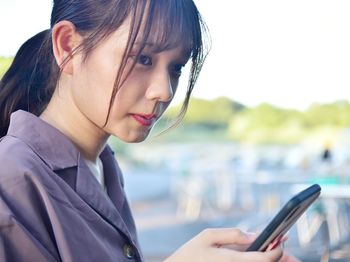 Close-up portrait of young woman using mobile phone