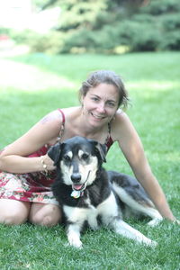 Close-up of young woman holding dog on field