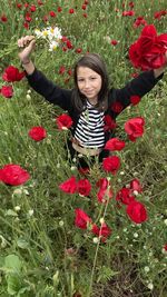 Portrait of girl standing amidst flowers on field