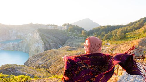 Rear view of woman wearing scarf standing against mountain