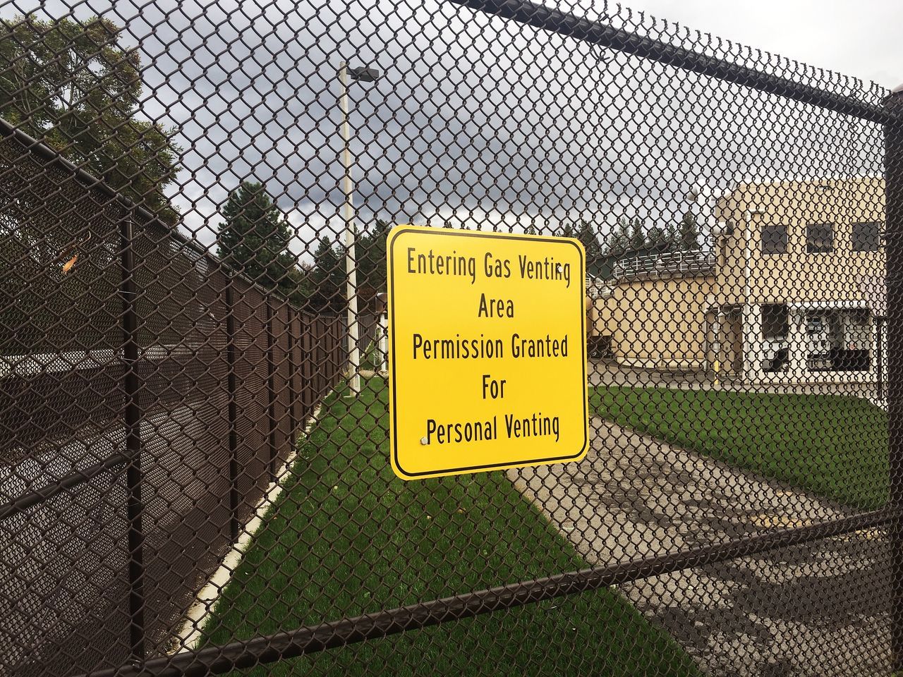 CLOSE-UP OF INFORMATION SIGN ON CHAINLINK FENCE AGAINST SKY