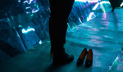 Low section of man standing on footpath at night