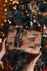 Female hands holding a christmas gift wrapped in festive beige paper festive winter holidays