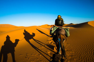 People riding horse in desert against sky