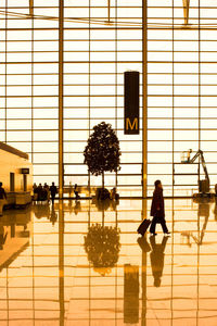 Silhouette of woman with umbrella walking on floor