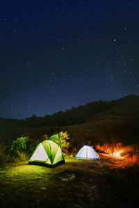 Illuminated tent on field against sky at night