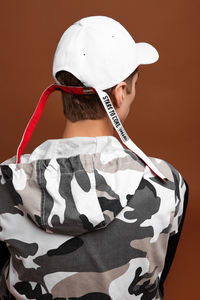 Rear view of boy wearing hat against gray background