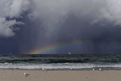 Scenic view of sea against rainbow in sky