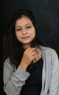 Portrait of beautiful young woman against black background