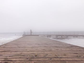 Pier over sea against foggy sky