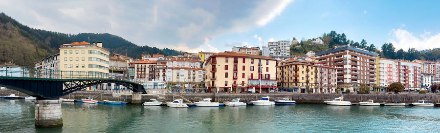 Buildings by river against sky