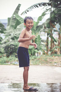 Full length of shirtless boy standing in water