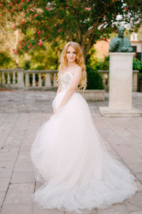 Portrait of bride wearing white dress standing outdoors