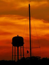 Silhouette of water tower against cloudy sky during sunset
