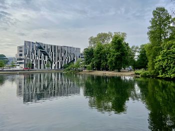 Scenic view of lake by trees against sky in city