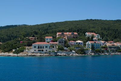 Scenic view of buildings and mountains against clear blue sky