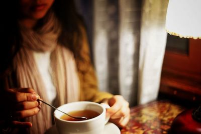 Midsection of woman stirring tea in cup