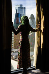 Rear view of silhouette woman standing by window