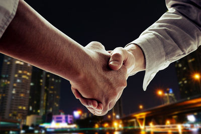 Midsection of couple holding hands at night