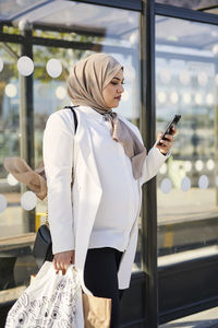 Woman using cell phone at bus stop