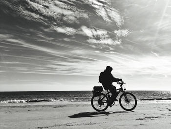 Side view of boy riding bicycle at beach