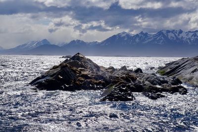 Scenic view of sea by mountains against sky